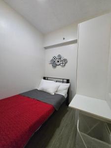 a small room with a bed with a red blanket at 2 Bedroom Suite in SM Marilao - Cheer Residence in Marilao