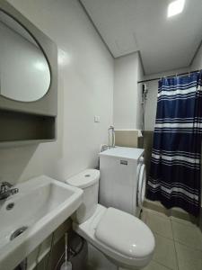 a bathroom with a toilet and a sink and a mirror at 2 Bedroom Suite in SM Marilao - Cheer Residence in Marilao +13 photos