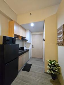 a kitchen with a black refrigerator and a door at 2 Bedroom Suite in SM Marilao - Cheer Residence in Marilao