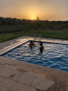 two people in a swimming pool at sunset at Villa Adam in Meknès