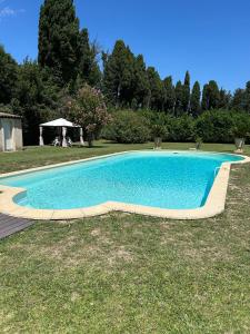 a swimming pool in the grass with a gazebo at Studio tout confort avec terrasse et piscine, idéal pour un séjour relax in Cabannes