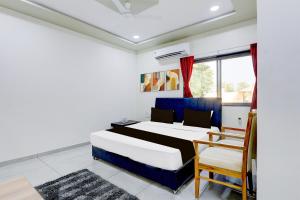 ein Schlafzimmer mit einem Bett und einem Stuhl und einem Fenster in der Unterkunft Hotel O RamdevGarh Resort in Ahmedabad