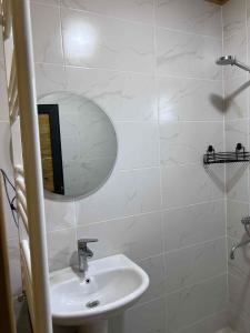 a white bathroom with a sink and a mirror at Khando's Resort in Passanauri