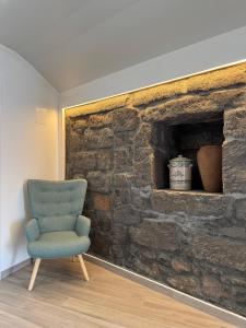 波瓦桑Raízes AL的石头壁炉前的一把蓝色椅子