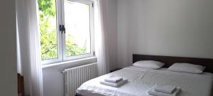Una cama blanca en una habitación con ventana. en Cherry Apartment, en Sarajevo 19 fotos más