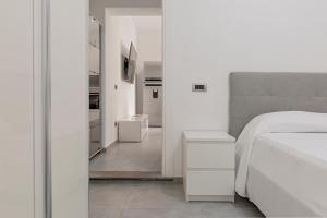 a white bedroom with a bed and a hallway at Homiday - Grey Apartment - Free Parking in Collesalvetti +15 photos