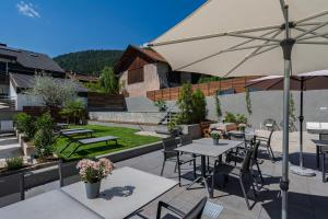 a patio with tables and chairs and an umbrella at Residence Alpina in Tesimo