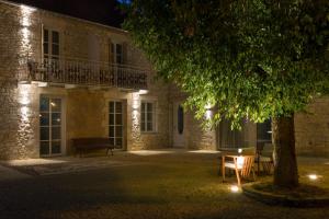 a building at night with a tree and a bench at Hôtel Maison Borrèze in Souillac