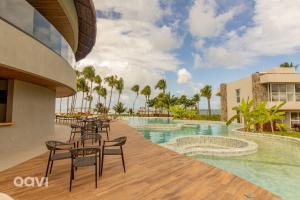 a resort pool with tables and chairs and palm trees at Naluum Residence Alto Padrão em Milagres By Qavi in Passo de Camarajibe