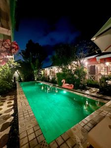 une piscine la nuit avec des gens dans l'eau dans l'établissement Secret Wooden Cabin - Lilac Suite, à Jimbaran