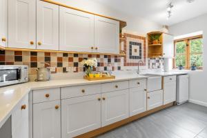 een keuken met witte kasten en een magnetron bij Kestrel Barn in Frocester