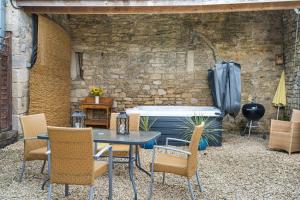 een patio met een tafel en stoelen en een bakstenen muur bij Kestrel Barn in Frocester