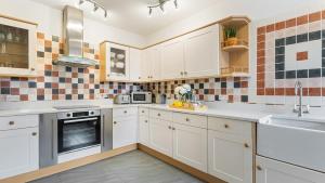 een keuken met witte kasten en een spoelbak bij Kestrel Barn in Frocester