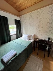 ein Schlafzimmer mit einem Bett und einem Schreibtisch mit einem Fenster in der Unterkunft Semi-detached cottage by the lake in Jyväskylä