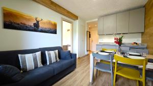a living room with a blue couch and a table at Hostdomus - Rainbow Apartment in Sestriere