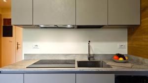 a kitchen with a sink and a bowl of fruit at Hostdomus - Rainbow Apartment in Sestriere