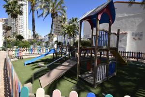 a playground with a slide in a park with palm trees at Rinconada Real - Fincas Arena in Benidorm