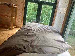 a bed in a room with a large window at Authentique, cosy et autonome en pleine nature in Clavier