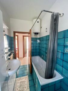a blue tiled bathroom with a tub and a sink at La porta del Gran Sasso in Montorio al Vomano