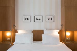 a bedroom with a white bed with three pictures on the wall at Hôtel Maison Borrèze in Souillac +75 photos