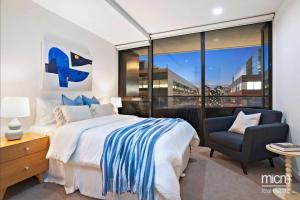 a bedroom with a bed and a chair and a window at Serrata - 2B2B Docklands Apt Parking Available in Melbourne