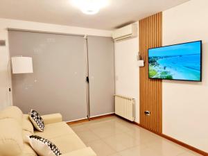 een woonkamer met een bank en een flatscreen-tv bij AC Suites XL in Puerto Madryn