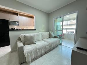 un salon avec un canapé et une cuisine dans l'établissement Apto Alto Padrão Aviação 2Qts (1Suíte), à Praia Grande