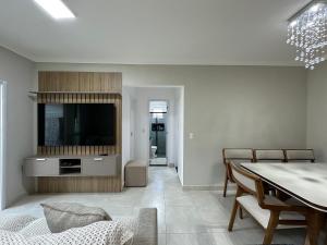 - un salon avec une télévision et une table à manger dans l'établissement Apto Alto Padrão Aviação 2Qts (1Suíte), à Praia Grande