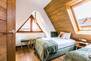 Un dormitorio con dos camas y una ventana. en Apartamenty Magia Tatr, en Kościelisko