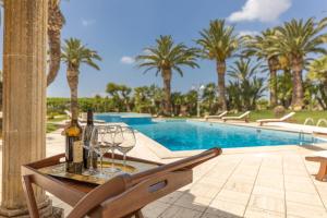 a table with wine bottles and glasses next to a swimming pool at Villa Oasi di Pace in Nardò