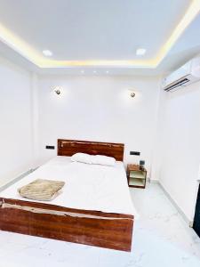 ボーパールにあるAtithi luxury home stayの白い部屋に木製ベッド1台が備わるベッドルーム1室 +4枚の写真