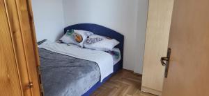 a small bed with a blue headboard in a room at Apartman Kovacevic Prnjavor Republika Srpska in Prnjavor