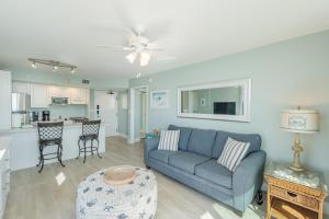 Una sala de estar con un sofá azul y una cocina. en Lovers Key #1106 by Sun Palace Vacations, en Fort Myers Beach