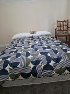 a blue and white comforter on a bed with a chair at Stay Near Colchester twn centre2 in Hythe