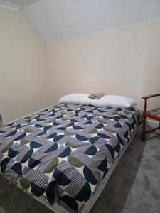 a bed with a blue and white comforter in a room at Stay Near Colchester twn centre2 in Hythe