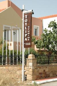 ein Schild für ein Hotel vor einem Haus in der Unterkunft Toulipa Rooms in Agia Ermioni