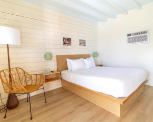 a bedroom with a bed and a chair and a lamp at Driftwood Motel in Bay Saint Louis