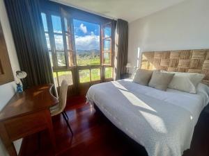 ein Schlafzimmer mit Bett, Schreibtisch und Fenster in der Unterkunft La casa roja de Ovio in Picones