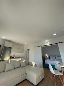 a living room with a white couch and a bed at Azzurro Boutique Apartaments in Sarandë