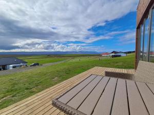 eine Holzterrasse mit einer Bank auf einem Feld in der Unterkunft Guesthouse Klambrasel in Skogar + 11 Fotos
