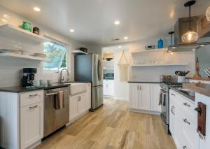 a kitchen with white cabinets and stainless steel appliances at Sea La Vie by Paradise Retreats in Ventura