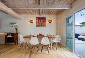 a dining room with a wooden table and white chairs at Sea La Vie by Paradise Retreats in Ventura