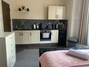a kitchen with white cabinets and a black stove at 155 Studio 1 - Uplands in Swansea