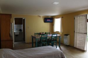 a bedroom with a dining room table and a television on the wall at Las Margaritas in Pila