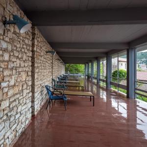 a row of benches against a brick wall with windows at Theoxenia Hotel in Andritsaina