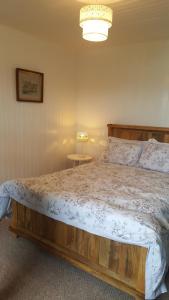 una camera da letto con un letto grande con testiera in legno di Tigh a Chaolais, Bosta House, Isle of Lewis 