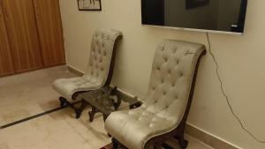 twee stoelen in een kamer met een tv bij Royal one cottage in Islamabad