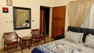een slaapkamer met een bed, 2 stoelen en een spiegel bij Royal one cottage in Islamabad
