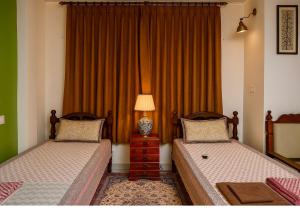 a bedroom with two beds and a lamp and a window at Diya Bed and Breakfast in New Delhi