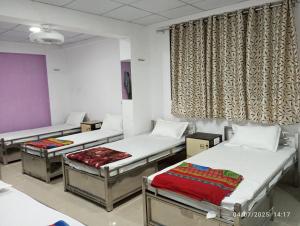 a room with three beds and a window at Shiv Sai Dormitory AC in Surat